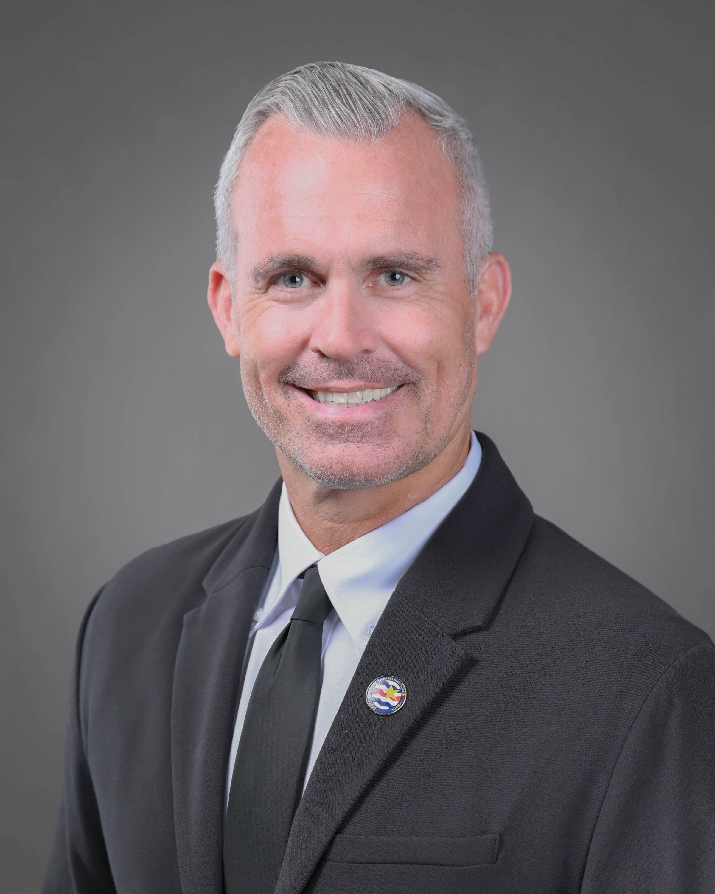 Smiling man with graying hair and a dark suit